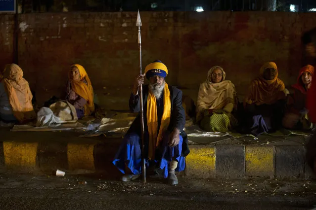 An Indian Sikh man looks on as others rest on a pavement outside a Sikh temple in New Delhi, India, Wednesday, January 27, 2016. (Photo by Tsering Topgyal/AP Photo)