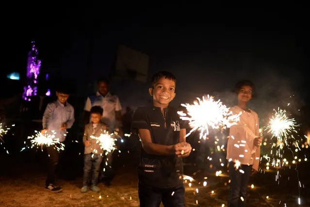 Children play with firecrackers at Madan Mohan Malviya Stadium as part of festivities celebrating Diwali festival in Prayagraj, India. Diwali, the annual Hindu festival of lights, will be celebrated on November 12, 2023. (Photo by Rajesh Kumar Singh/AP Photo)
