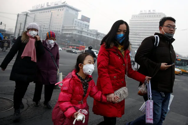 People wear face masks as they cross a street on a polluted day in Beijing, China January 4, 2017. (Photo by Thomas Peter/Reuters)