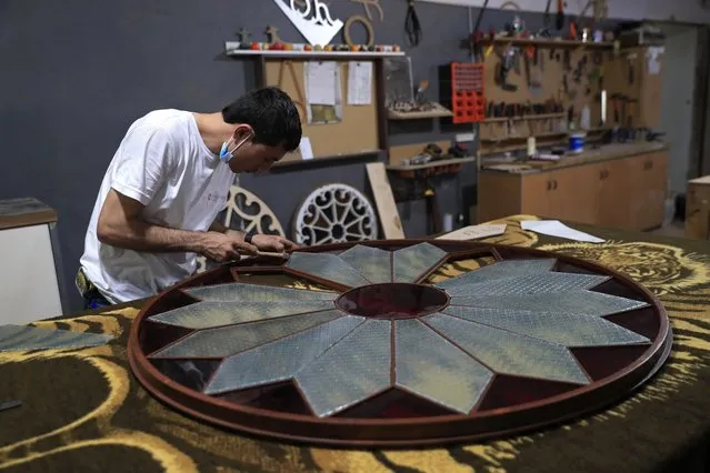 A carpenter works on restoring part of a door's windows glass that was shattered in a massive explosion last August in the Beirut port, at a workshop in Bsous village, Lebanon, Monday, June 28, 2021. The 60-year-old Sursock Museum is still rebuilding a year after the explosion. It was the beating heart of Beirut's arts community, and some hope that reopening it will be a first step in the harder task of rebuilding the city's once thriving arts scene. (Photo by Hussein Malla/AP Photo)