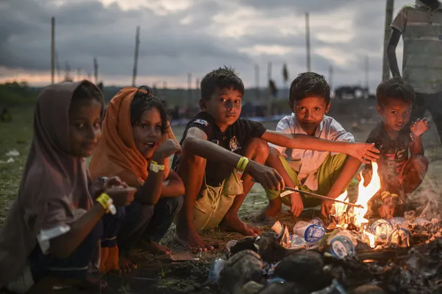 Ethnic Rohingya children sit around a fire at their camp near a beach in Pidie, Aceh province, Indonesia, Friday, December 15, 2023. Since November, more than 1,500 Rohingya refugees fleeing Bangladesh by boat have landed in Indonesia's northern province of Aceh, three-quarters of them women and children. With so many Rohingya attempting the crossing in recent weeks, nobody knows how many boats did not make it, and how many people died. (Photo by Reza Saifullah/AP Photo)