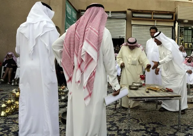 In this April 16, 2015 photo, Saudi men bargain to buy traditional Saudi swords and daggers at al-Aqeeliya open-air auction market in Riyadh, Saudi Arabia. (Photo by Hasan Jamali/AP Photo)
