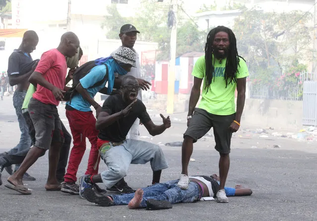 People react next to the dead body of a man during anti-government protests in Port-au-Prince, Haiti, February 12, 2019. (Photo by Jeanty Junior Augustin/Reuters)