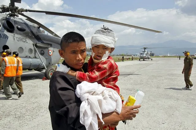 A man carries an injured child, who was wounded in Saturday's earthquake, after Indian Army soldiers evacuated them from Trishuli Bazar to the airport in Kathmandu, Nepal, April 27, 2015. (Photo by Jitendra Prakash/Reuters)
