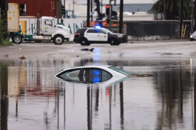 A car sits partially submerged on a flooded road during a rain storm in Long Beach, California, on February 1, 2024. The US West Coast was getting drenched February 1, 2024 as the first of two powerful storms moved in, part of a “Pineapple Express” weather pattern that was washing out roads and sparking flood warnings. (Photo by David Swanson/AFP Photo)