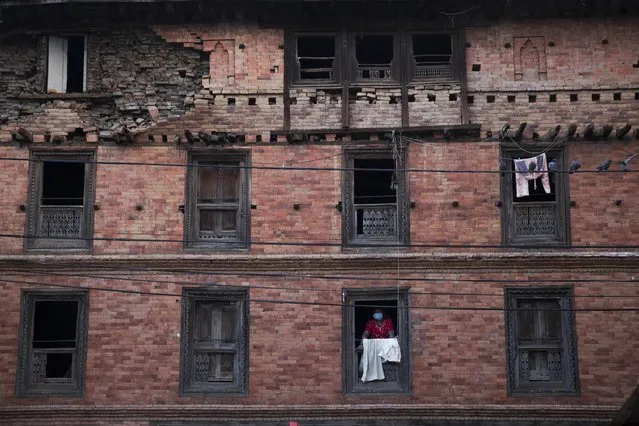 A woman looks from the window of a house that was damaged during the April 25 earthquake in Sakhu, Nepal, Wednesday, May 6, 2015. (Photo by Bernat Amangue/AP Photo)