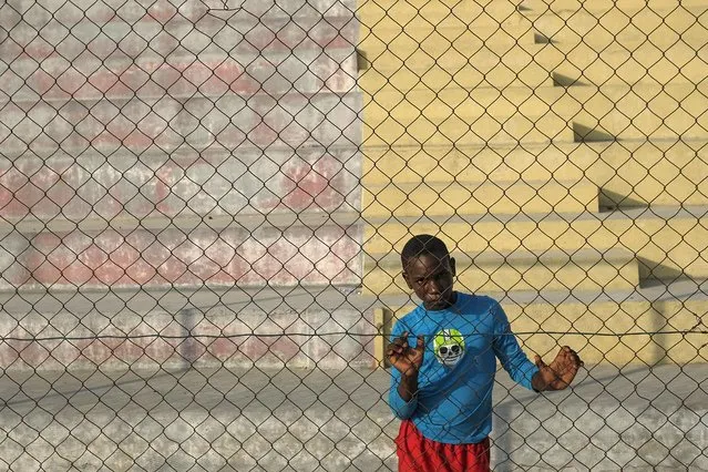 A youth stands at a gate on a dirt field at the Hugo Chavez Square in Port-au-Prince, Haiti, Thursday, October 28, 2021. (Photo by Matias Delacroix/AP Photo)