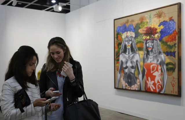 Visitors chat in front of an artwork created by Bali-based artist Ashley Bickerton during the VIP preview of the art fair “Art Basel” in Hong Kong, Tuesday, March 22, 2016. (Photo by Kin Cheung/AP Photo)