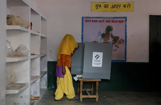 A woman looks at the Electronic Voting Machine (EVM) before casting her vote inside a booth at a polling station during the state assembly election in Hapur, in the central state of Uttar Pradesh, India, February 11, 2017. (Photo by Adnan Abidi/Reuters)