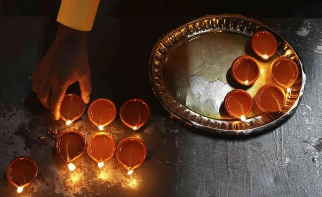 A Sri Lankan ethnic Tamil man offers a tray of oil lamps during Diwali, the Hindu festival of lights, in Colombo, Sri Lanka, Thursday, November 4, 2021. (Photo by Eranga Jayawardena/AP Photo)