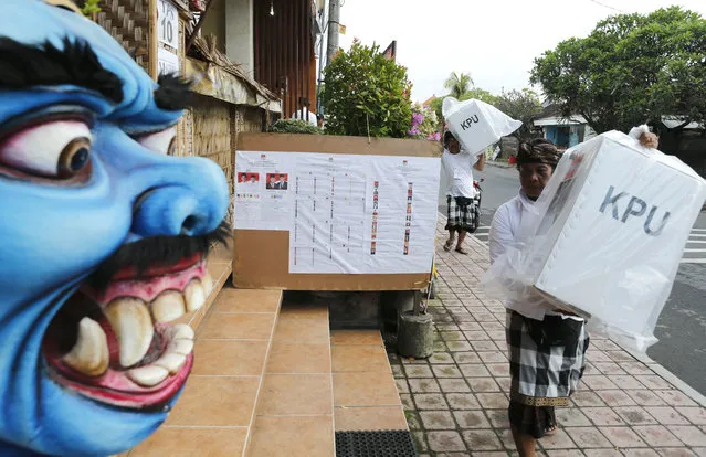 Election officials carry ballot boxes before the start of voting during presidential and legislative elections at a polling station in Bali, Indonesia, Wednesday, April 17, 2019. About 193 million people are eligible to vote in polls that will decide who leads the world's most populous Muslim-majority nation. (Photo by Firdia Lisnawati/AP Photo)