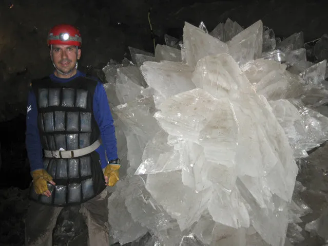 In this image provided by Mike Spilde, Mario Corsalini stands near to a gypsum rosette crystal. In a Mexican cave system so beautiful and hot that it is called both Fairyland and hell, scientists have discovered life trapped in crystals that could be 50,000 years old. The bizarre and ancient microbes were found dormant in caves in Naica, Mexico, and were able to exist by living on minerals such as iron and manganese, said Penelope Boston, head of NASA's Astrobiology Institute. (Photo by Mike Spilde via AP Photo)