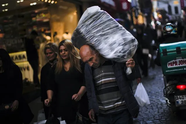 A man carries goods on his back in a commercial area in Istanbul, Turkey, Tuesday, November 2, 2021. Many Turkish consumers are faced with increased hardship as prices of food and other goods have soared in recent years. The yearly consumer price index increased by 19.9% in October, up from 19.58% in September, according to official data by the Turkish Statistical Institute released on Nov. 3. (Photo by Francisco Seco/AP Photo)