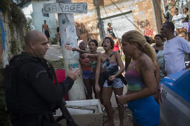 Residents shout at a Special Operations Battalion (BOPE) Police officer after the bodies of two men were found in the Sao Carlos slum complex in Rio de Janeiro, Brazil, Friday, May 15, 2015. (Photo by Ricardo Moraes/Reuters)