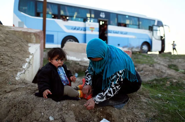 A woman, who just fled a village controled by Islamic State militants, checks her daughter as she sits in front of a bus before heading to the camp at Hammam Ali, south of Mosul, Iraq February 22, 2017. (Photo by Zohra Bensemra/Reuters)
