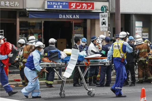 First responders carry a stretcher after a deadly fire at an eight-story building in a major business, shopping and entertainment district in Osaka, western Japan, Friday, December 17, 2021. More than 20 people were feared dead after the fire broke out Friday in the building in Osaka, officials said, and police were investigating arson as a possible cause. (Photo by Yukie Nishizawa/Kyodo News via AP Photo)