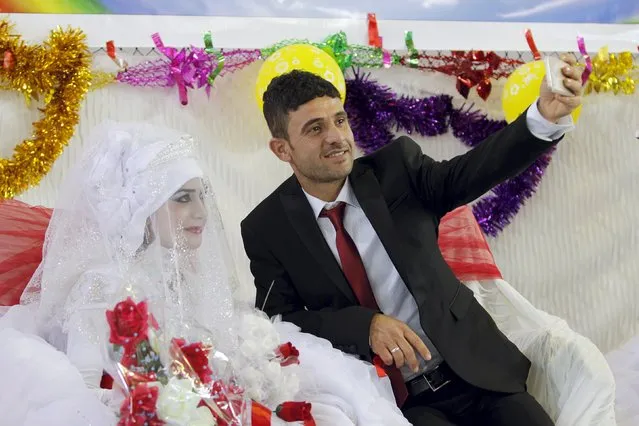 A groom takes a selfie with his bride during a mass wedding ceremony for Turkmen who are displaced and have fled the violence in the province of Nineveh, in Kirkuk, Iraq, April 7, 2016. (Photo by Ako Rasheed/Reuters)