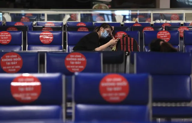 A passenger uses a phone while waiting to board a flight at Tan Son Nhat airport in Ho Chi Minh city, Vietnam Friday, October 15, 2021. Vietnam has resumed air travel after several months of suspension due to COVID-19 outbreak. (Photo by Hau Dinh/AP Photo)