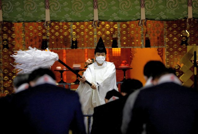 A Shinto priest wearing a protective face mask presides a ceremony as visitors offer prayers on the first business day of the New Year at the Kanda Myojin shrine, frequented by worshippers seeking good fortune and prosperous business, amid the coronavirus disease (COVID-19) outbreak, in Tokyo, Japan, January 4, 2022. (Photo by Kim Kyung-Hoon/Reuters)