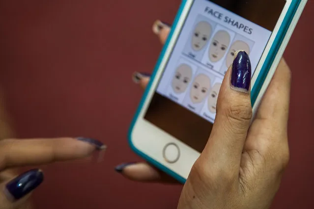 A Sun Model student learns how to identify different facial shapes using  a mobile application as part of her training at the fashion school on March 31, 2014 in Phnom Penh, Cambodia. (Photo by Omar Havana/Getty Images)