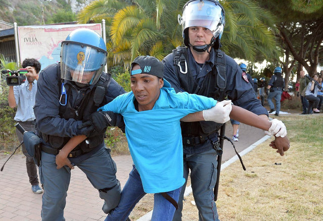 Italian police officers drag a migrant away in Ventimiglia, at the Italian-French border Tuesday, June 16, 2015. Police at Italy's Mediterranean border with France have forcibly removed some of the African migrants who have been camping out for days in hopes of continuing their journeys farther north. The migrants, mostly from Sudan and Eritrea, have been camped out for five days after French border police refused to let them cross. (Luca Zennaro/ANSA via AP)