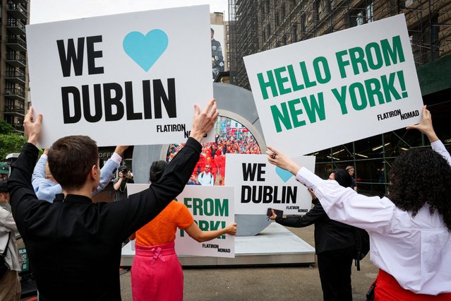 People hold signs as they greet during the reveal of The Portal, a public technology sculpture that links with direct connection between Dublin, Ireland and the Flatiron district in Manhattan, in New York City on May 8, 2024. (Photo by Brendan McDermid/Reuters)