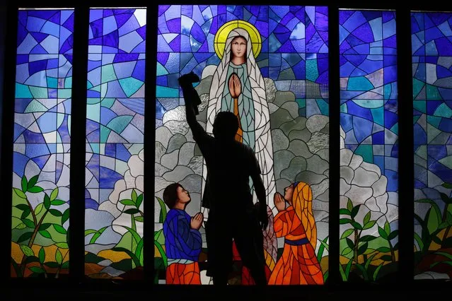 A worker cleans mosaic glass window at Barnabas Church ahead of Christmas Eve in Tangerang, Indonesia, 23 December 2021. The world's most populous Muslim country is gearing up for Christmas celebration as 217,000 police officers would be deployed to protect thousands of churches and other religious sites in the country. (Photo by Adi Weda/EPA/EFE)