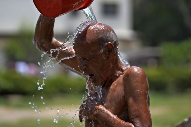A man cools off himself during a hot summer day at a park in Karachi, Pakistan, Tuesday, May 21, 2024. Authorities in Pakistan on Tuesday urged people to stay indoors as the country is hit by an extreme heat wave that threatens to bring dangerously high temperatures and yet another round of glacial-driven floods. (Photo by Fareed Khan/AP Photo)