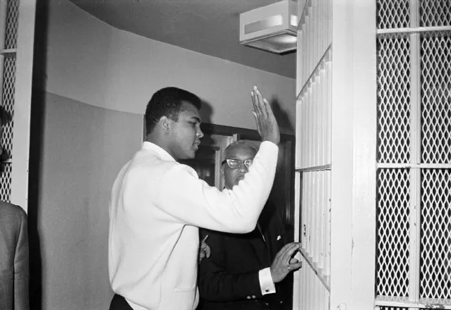 Former heavyweight boxing champ Muhammad Ali pats the bars on the door of the Dade County jail, December 16, 1968, as he starts serving a 10-day sentence on an old traffic charge.  Ali said this would be good training if he has to serve his five-year term for draft dodging.  The former champion surrendered voluntarily today and is accompanied by his attorney Henry Arrington. (Photo by AP Photo)