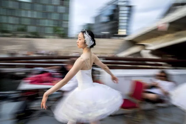 A dancer from the Berlin State Ballet dances “Swan Lake” on an excursion boat during a tour of the city centre in Berlin, Germany on June 10, 2021. The performance was followed by numerous people along the route. (Photo by Christoph Soeder/dpa)
