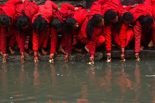 Hindu devotees wait to fill pots with water from the Bagmati River at the Pashupatinath temple during the month-long Swasthani festival in Kathmandu on February 1, 2022. (Photo by Prakash Mathema/AFP Photo)
