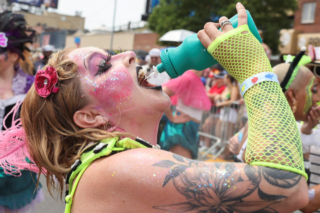 A person participating in the Mermaid Parade stops to drink water during a heatwave in Coney Island, Brookly, New York City, U.S., June 22, 2024. (Photo by Caitlin Ochs/Reuters)