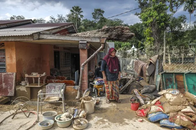 A tree trunk is seen atop the roof damaged house as owner walks after the flooding a day earlier at Kuala Langat, 15KM from Kuala Lumpur, Malaysia, 20 December 2021. Several Malaysian states has been struck by floods caused by two days of heavy rain leaving five killed and 61,000 of residents to be evacuated with many trapped in their vehicles and homes. (Photo by Fazry Ismail/EPA/EFE)