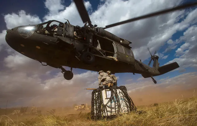 In this September 23, 2014 file photo, Spc. Melissa Evalle, left, and Spc. Gabriel Torres battle the wind and dirt as a Sikorsky UH-60 Black Hawk flies lower so they can attach a load of supplies to the bird during training down range at Fort Carson in Colorado Springs, Colo. Lockheed Martin on Monday, July 20, 2015 said it is buying Black Hawk helicopter maker Sikorsky Aircraft for $9 billion. (Photo by Christian Murdock/The Gazette via AP Photo)
