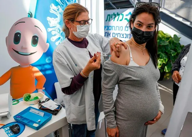 A health worker administers a dose of the Pfizer-BioNtech COVID-19 coronavirus vaccine to a pregnant woman at Clalit Health Services, in Israel's Mediterranean coastal city of Tel Aviv on January 23, 2021. Israel began administering novel coronavirus vaccines to teenagers as it pushed ahead with its inoculation drive, with a quarter of the population now vaccinated, health officials said. (Photo by Jack Guez/AFP Photo)