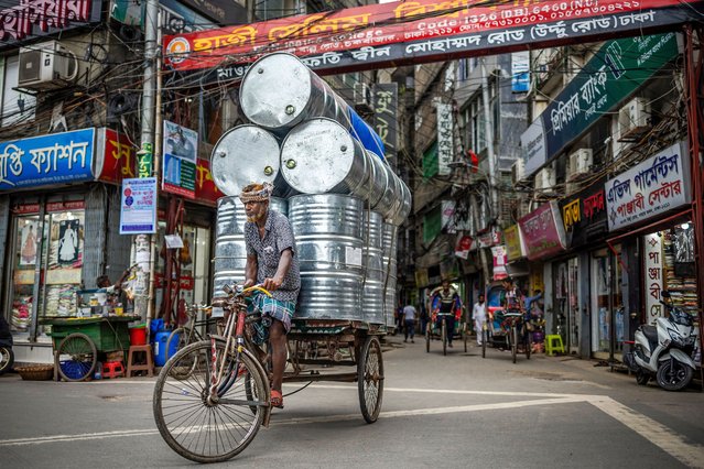 A man carries steel drums on his cart along a street in Old Dhaka on August 17, 2024. (Photo by Luis Tato/AFP Photo)