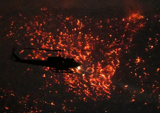 A helicopter is silhouetted by glowing embers as it makes a water drop at the “Old Fire”, which burned in Calabasas, California, U.S., June 4, 2016. (Photo by Gene Blevins/Reuters)