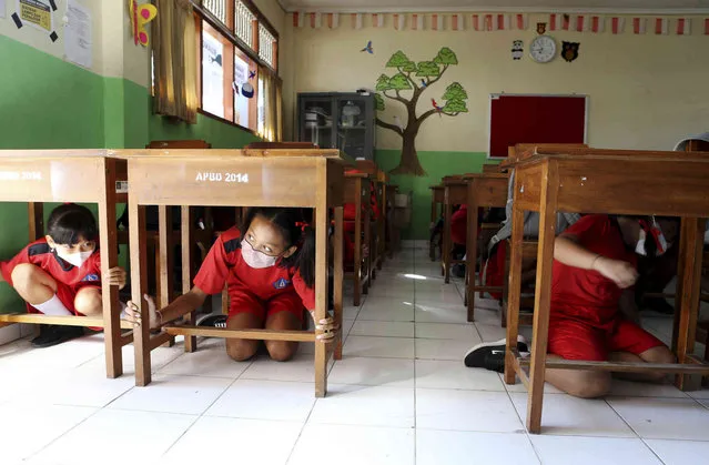 Elementary students shelter under their desks during an emergency drill that assumed a major earthquake and tsunami in Bali, Indonesia on Tuesday, May 24, 2022. (Photo by Firdia Lisnawati/AP Photo)