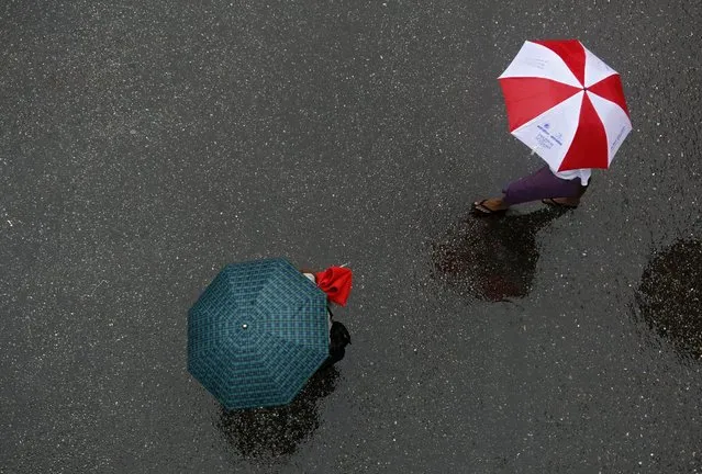 People cross a road as they shelter under umbrellas during heavy rain in Yangon, Myanmar, 24 May 2016. Myanmar this year gets it's early monsoon as cyclone Roanu brought rainfall after suffering recorded extreme temperatures. Myanmar monsoon normally starts at the beginning of June and ends in September. (Photo by Lynn Bo Bo/EPA)