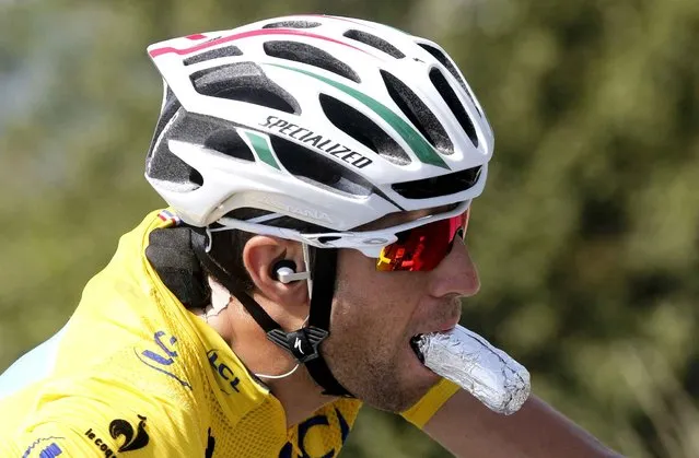 Italy's Vincenzo Nibali, wearing the overall leader's yellow jersey, eats while riding in the pack during the thirteenth stage of the Tour de France cycling race over 197.5 kilometers (122.7 miles) with start in Saint-Etienne and finish in Chamrousse, France, Friday, July 18, 2014. (Photo by Christophe Ena/AP Photo)