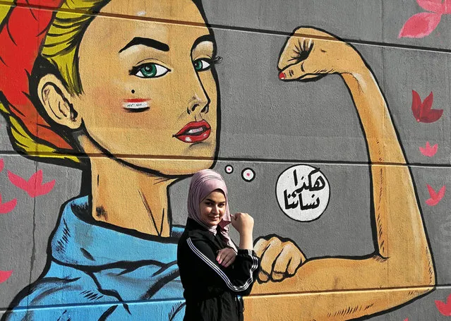 A woman poses for a picture near a graffiti with Arabic reading “those are our women” during ongoing protests near Tahrir Square in Baghdad, Iraq, Thursday, November 7, 2019. (Photo by Khalid Mohammed/AP Photo)