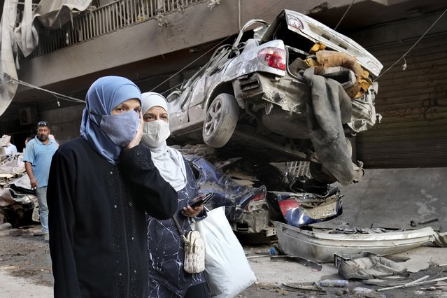 Lebanese women pass next of destroyed cars, at the site of Thursday's Israeli airstrike, in Beirut, Lebanon, Friday, October 11, 2024. (Photo by Hussein Malla/AP Photo)