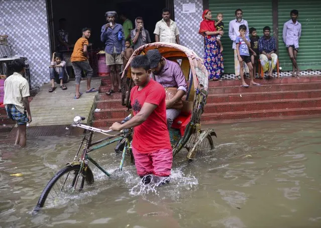 A rickshaw puller wades through flood waters in Sylhet, Bangladesh, Monday, June 20, 2022. Floods in Bangladesh continued to wreak havoc Monday with authorities struggling to ferry drinking water and  dry food to flood shelters across the country’s vast northern and northeastern regions. (Photo by Mahmud Hossain Opu/AP Photo)
