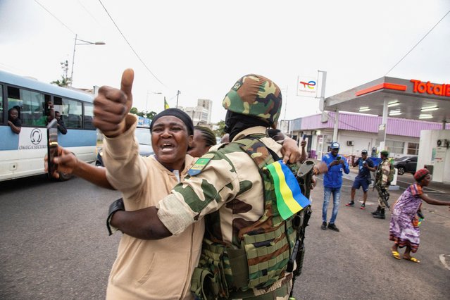 A woman embraces a soldier as she celebrates with people in support of a putschists, in a street of Port-Gentil, Gabon on August 30, 2023. (Photo by Reuters/Stringer)