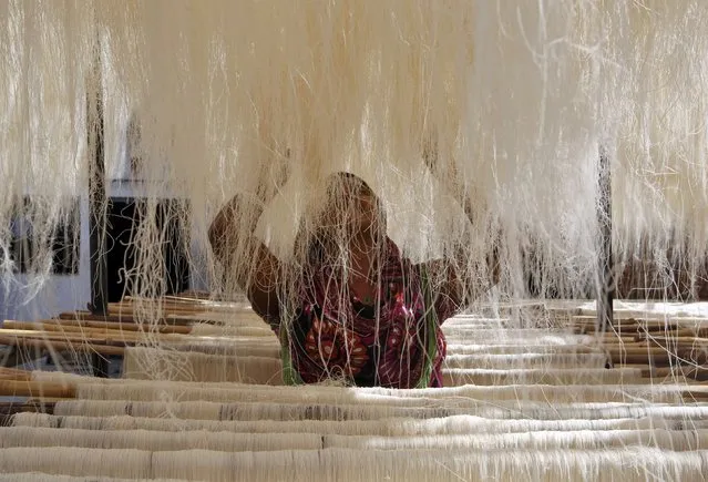 A woman arranges strands of vermicelli, a specialty eaten during the Muslim holy fasting month of Ramadan, which are kept out to dry at a factory in Allahabad, India, June 29, 2016. (Photo by Jitendra Prakash/Reuters)