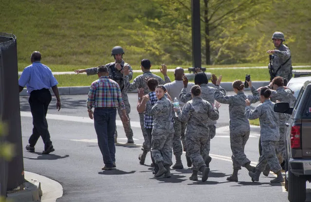 Hands raised, people are escorted out of the Malcolm Grow Medical facility on Andrews AFB in  Morningside, MD on June 30, 2016. The Base was on lockdown due to an exercise in which snowballed into a security and media frenzy. (Photo by Linda Davidson/The Washington Post)