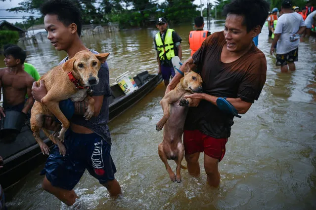 Residents carry their dogs to a boat as floodwaters submerged areas of Ye township in Mon State on August 11, 2019. Myanmar troops deployed to flood-hit parts of the country on August 11 to help with relief efforts after rising waters left thousands stranded and the death toll from a landslide jumped to 51. (Photo by Ye Aung Thu/AFP Photo)