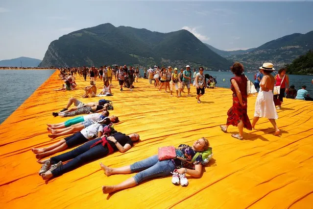 People enjoy the sun on the installation “The Floating Piers” on Lake Iseo by Bulgarian-born artist Christo Vladimirov Yavachev, known as Christo, at the installation's last weekend near Sulzano, northern Italy, July 2, 2016. (Photo by Wolfgang Rattay/Reuters)