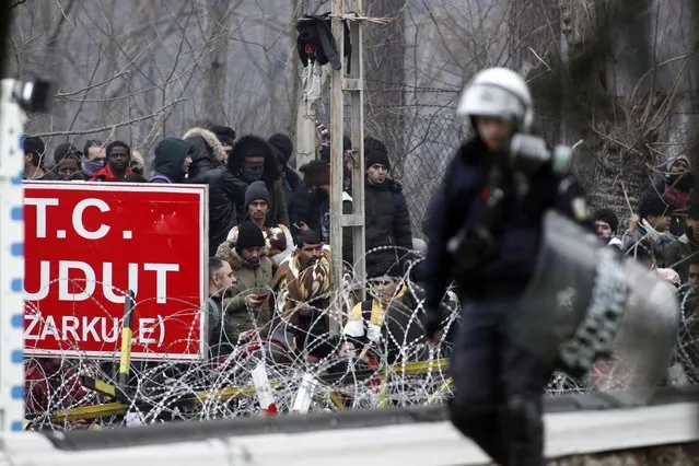 A Greek riot policeman patrols the border gate in Kastanies village as migrants trying to enter Greece from the Pazarkule border gate, Edirne, Turkey, gather at the Greek-Turkish border Saturday, February 29, 2020. (Photo by Giannis Papanikos/AP Photo)