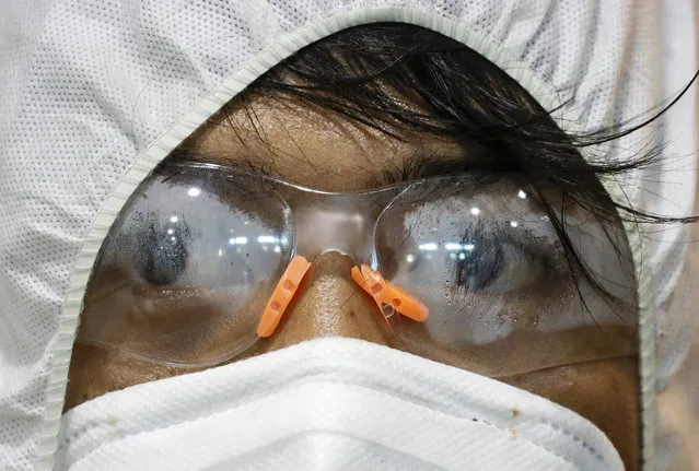 Mist is seen on the googles of a worker wearing a protective suit as he disinfects the city hall of Marikina, in Manila, Philippines on Friday, March 13, 2020. The Philippine president announced Thursday domestic travel to and from metropolitan Manila will be suspended for a month and authorized sweeping quarantines in the crowded capital to fight the new coronavirus. For most people, the new coronavirus causes only mild or moderate symptoms. For some it can cause more severe illness. (Photo by Aaron Favila/AP Photo)